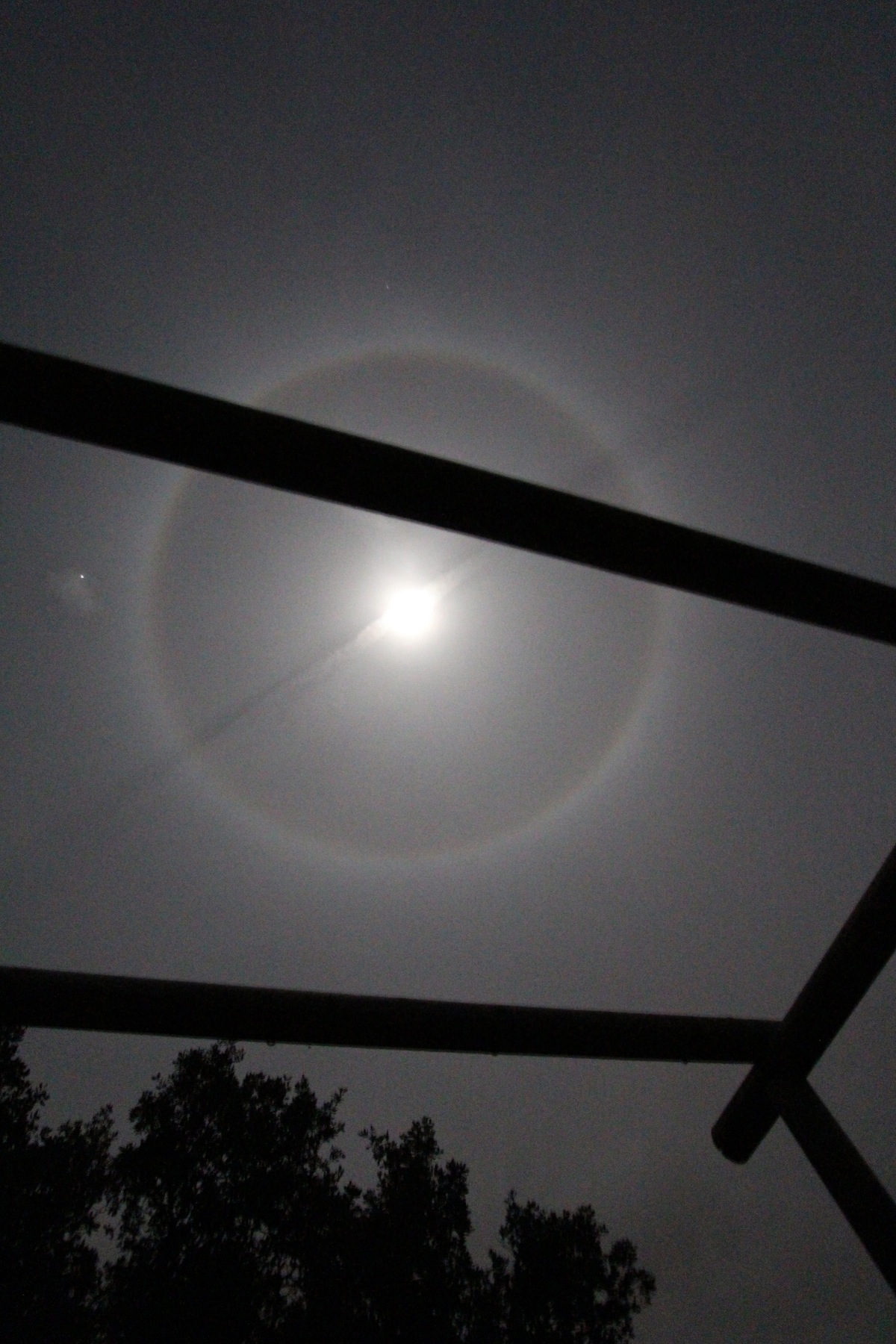 Halo moon with contrail right through the centre and tiny Jupiter to